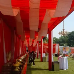 This is a view of the catering section under a large red and white tent at a daytime event. I ensure all parts of the event space are well-decorated and functional.