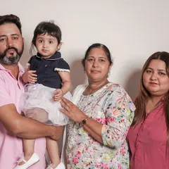 A classic family portrait with three generations, taken against a clean white backdrop during an in-home studio session.