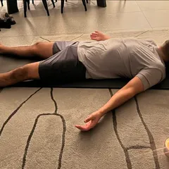 Guiding a client into Savasana, or corpse pose, at the end of a private session. We often use a candle to create a calming atmosphere for deep relaxation.