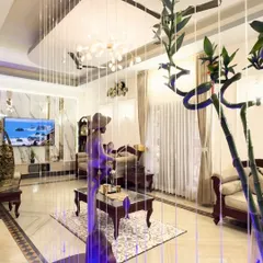 We incorporated a stunning string water feature to act as a visual partition in this living room, adding a dynamic and luxurious element. The design combines traditional furniture with modern lighting and a marble-clad TV wall for a rich, layered look.
