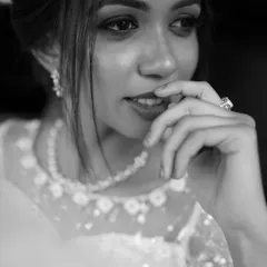 A thoughtful black and white portrait of a bride, highlighting her expression and the details of her ring and necklace.