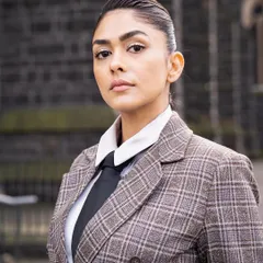A serious, confident portrait. The tailoring of this custom suit is impeccable, creating a strong and commanding silhouette.