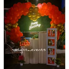 This vibrant setup combines a lush red and gold balloon arch with a "Happy Birthday" neon sign, creating a perfect photo booth. We also included 'BABY' display blocks and tiered pedestals for the cake and other decor elements.