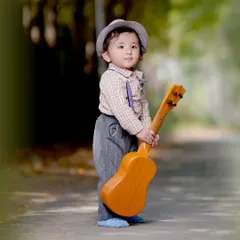 A toddler stands on a path holding a small guitar, a great prop for adding a playful element to outdoor kids' photography.