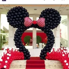 A classic Minnie Mouse themed entrance arch. The iconic Minnie ears and bow are created with black and red balloons, setting the stage for a fun and memorable party.