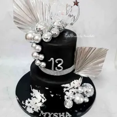 A glamorous black and silver disco party cake for a 13th birthday. This two-tier cake is decorated with disco balls, silver leaf, and sparkling rhinestones.