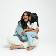 A mother and daughter sharing a moment of pure, uninhibited laughter in the studio. My clean, white backdrop ensures that nothing distracts from the genuine connection and happiness between them.