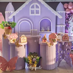Amayra's fairy garden party featured this lovely purple castle backdrop. We used fluted pedestals for desserts, butterfly cutouts, and a neon '3' to mark her special day, creating a perfect spot for photos.