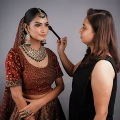A student carefully applies blush during a bridal makeup exam. I create a professional setting for assessments to prepare them for the pressures of a real job.