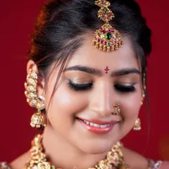 A close-up of a radiant bridal look. The focus here is on shimmering gold eyeshadow that makes the eyes pop, paired with flawless skin and traditional temple jewelry for a divine finish.