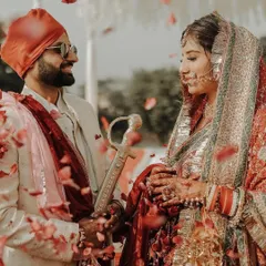 An intimate glance between the bride and groom during their Anand Karaj ceremony. The shower of petals adds a touch of magic to this sacred Sikh wedding moment.