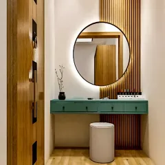 A chic floating dressing table with a backlit round mirror and fluted wood paneling, creating a perfect personal grooming corner.