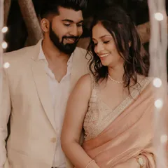 A sweet, smiling portrait of the newly engaged couple, framed by the soft glow of decorative lights.