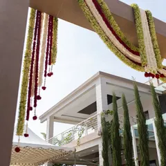 A low-angle shot looking up at the festive flower garlands decorating the entrance of a home for a traditional ceremony.