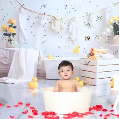 A half-birthday celebration with a fun splash session. The "1/2" sign adds a unique touch to this shot of a baby enjoying a bath with rose petals and bubbles.