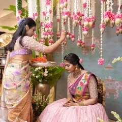 A family member blesses the bride during a pre-wedding ritual. The decor, with its hanging flowers and traditional elements, creates a sacred space that honors these heartfelt moments.