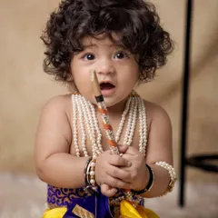 A close-up portrait of a baby Krishna with his flute and beautiful pearl necklaces. I focus on capturing these innocent, curious expressions that make each photo a unique treasure.