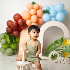 A portrait from a jungle-themed first birthday shoot, complete with a wooden tricycle and colorful balloon arch. I provide a variety of props to make every session unique.