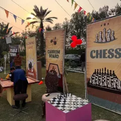 More game stations at the pre-wedding event, including carrom and a bowling game, all presented with colorful and festive banners.