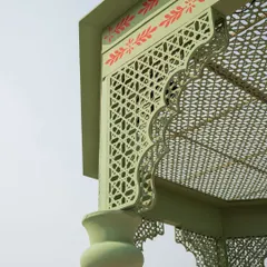 A close-up of the intricate jali cutwork and hand-painted motifs on the mandap structure. These details are inspired by the architectural elements of Mughal palaces.