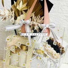 A handheld view of the all-white luxury hamper, showing the beautiful arrangement of gifts inside the daisy-printed PVC bag.