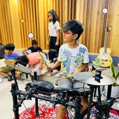 A young camper gets his first taste of playing the drums. Our camp lets kids try out various instruments to discover what they're passionate about.
