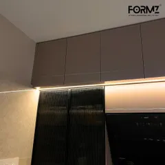 A detailed shot of fluted glass cabinet doors paired with handleless upper cabinets. The under-cabinet lighting highlights the texture of the glass and creates a warm, inviting glow on the countertop.