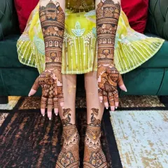 This bride's feet are adorned with elegant elephant and peacock motifs, perfectly matching the traditional designs on her hands.