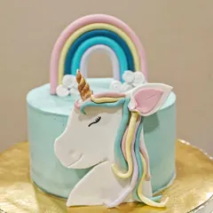 A full view of the unicorn theme cake. The simple, smooth buttercream finish makes the colorful fondant details really stand out.