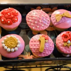 It's all in the details. These custom-designed cupcakes were part of the dessert table, featuring intricate fondant work with flowers, bows, and a number '1' to celebrate the special milestone.