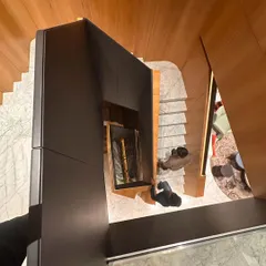 An overhead perspective of a staircase, highlighting the dynamic interplay of wood, grey matte paint, and marble. This view emphasizes the fluidity of the design, which guides movement while acting as a central art piece.