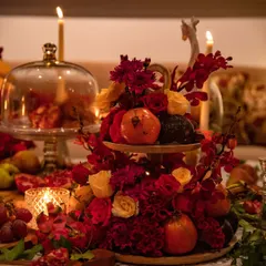 A two-tiered arrangement featuring a mix of red and yellow roses, pomegranates, and other botanicals. This piece serves as a focal point, demonstrating how I integrate edible elements directly into the floral design.