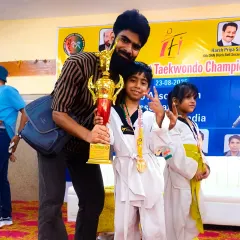 A proud moment with a young champion holding his trophy at the 16th North-East District Taekwondo Championship.
