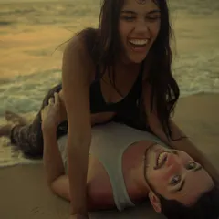 Capturing the playful, candid side of your relationship is just as important. This warm, golden-hour shot shows a moment of pure laughter and fun on the sand during a beach engagement session.
