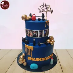 A two-tiered gym-themed cake for a fitness enthusiast. The cake is decorated with edible dumbbells, kettlebells, and a photo strip of workout pictures, all in a bold blue and gold design.