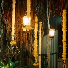 This nighttime view highlights the magical ambiance created by combining floral garlands and vintage lanterns. The decor, set against the dark backdrop of foliage, is perfect for an evening wedding or festival.