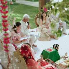 A candid moment from an outdoor wedding ceremony. The families are involved, and the atmosphere is full of love and happiness.