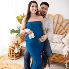 A proud and happy portrait of the parents-to-be. Holding a pair of baby shoes, they look at the camera, ready and excited for their new roles as mom and dad.