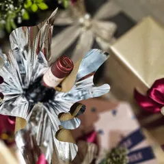 I love finding creative ways to wrap items, like this bottle of wine. Here, I used a dramatic silver and gold foil wrap that adds a celebratory and glamorous feel to the hamper.