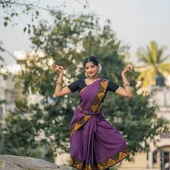 A graceful pose captured during a photoshoot at a temple. The setting provides a serene and powerful backdrop that complements the traditional aesthetics of Bharatanatyam.