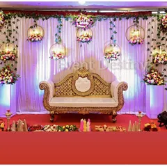 A dreamy and elegant stage setup for an engagement ceremony. We used hanging golden rings adorned with flowers, set against a soft, illuminated purple and white curtain backdrop to create a magical atmosphere.