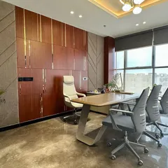 This executive cabin balances authority with modern design. The room features a custom wood-paneled wall with metallic inlays, a sleek executive desk, and large windows for ample natural light, creating a productive and sophisticated leadership space.