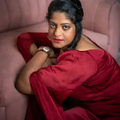 Vidyasri's portrait is a story of quiet strength. Here, she is seated by a pink couch, her expression a mix of softness and resilience. The lighting is designed to feel gentle yet defining, capturing her essence as a mother and professional who is reclaiming a moment for herself.