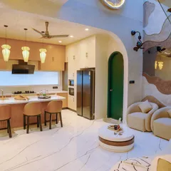 Our design philosophy is about creating spaces that flow. This open-concept area seamlessly connects the living room and a bespoke kitchen, unified by organic curves, a warm colour palette, and a double-height wall that adds a sense of grandeur.