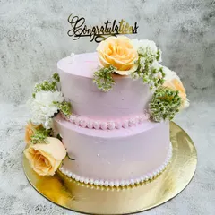 A simple and elegant two-tier cake for a lovely engagement party. The soft pink buttercream is adorned with a cascade of fresh peach roses and white carnations, creating a romantic and classic look.
