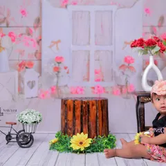Sitting pretty among the flowers. This photo captures a quiet, sweet moment with the baby girl looking curious in her beautiful garden setting.