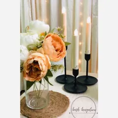 A simple yet elegant tabletop arrangement featuring beautiful peonies and modern black candlestick holders with safe, battery-operated LED candles. This kind of detail adds a touch of class to any romantic setup.