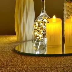 A close-up of a glittering gold tablescape. The warm glow from the LED candles reflects beautifully on the mirrored base and shimmery tablecloth, creating a luxurious and inviting atmosphere.