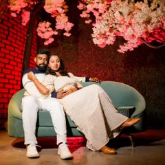 A relaxed indoor shot of the couple on a modern sofa. The cherry blossom backdrop adds a beautiful, romantic touch to the scene.