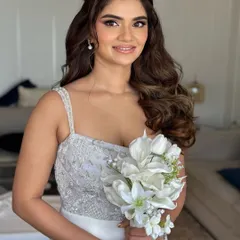 A beautiful bride ready for her white wedding or reception. Her look is soft and glamorous, with voluminous waves and a radiant smile.